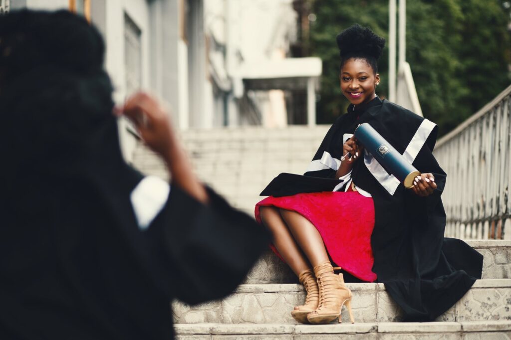 woman wearing black graduation coat sits on stairs